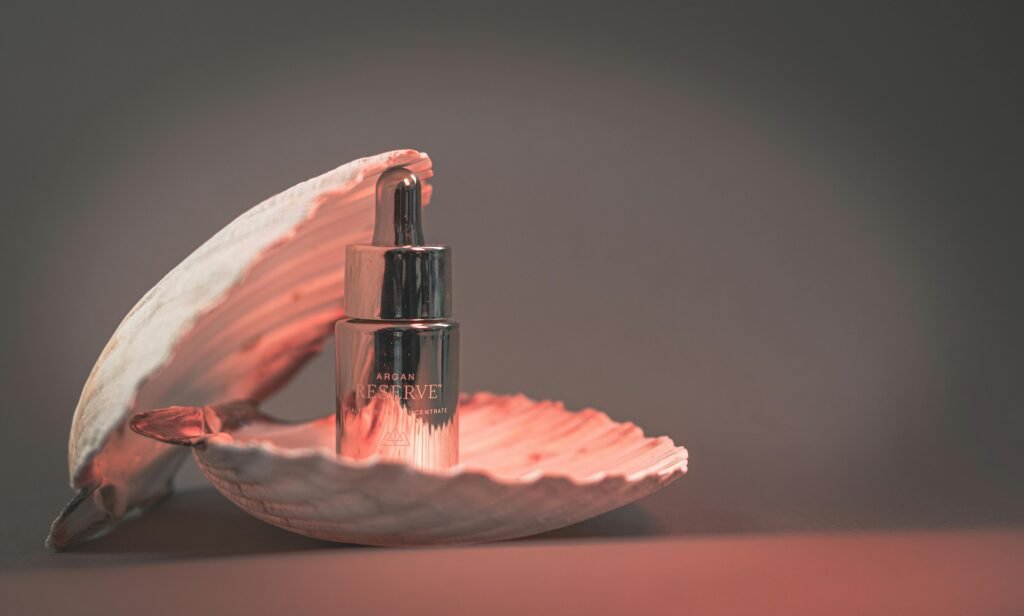 A stylish argan oil bottle elegantly placed inside an open seashell, set against a soft backdrop.